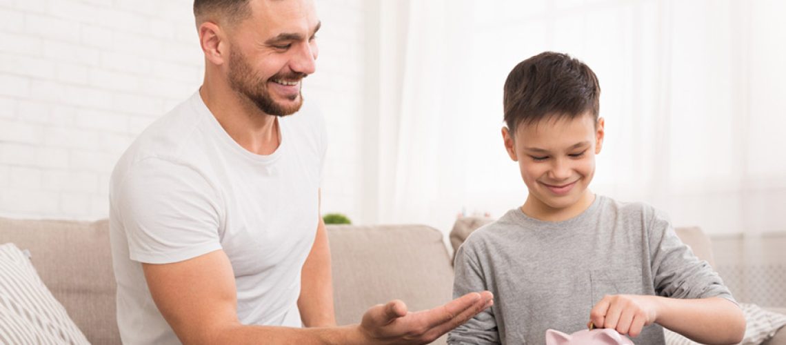 father sitting on lounge teaching son how to budget with finances
